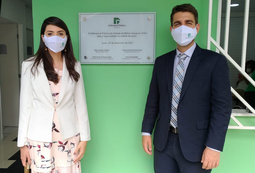 Defensora pública Rebeca Lima e Silva e o defensor público Raphael Varga posam junto à placa de inauguração da unidade de Ipiaú